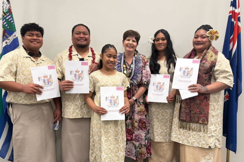 Five new citizens holding their citizenship certificates with a woman wearing mayoral chains at a Porirua citizenship ceremony.
