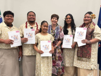 Five new citizens holding their citizenship certificates with a woman wearing mayoral chains at a Porirua citizenship ceremony.