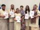 Five new citizens holding their citizenship certificates with a woman wearing mayoral chains at a Porirua citizenship ceremony.