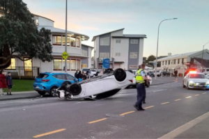 A white car lies upside down on Moorefield Road in Johnsonville as police attend the crash scene.