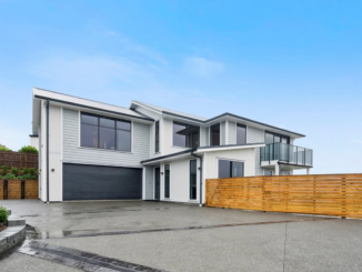 Modern two-storey Porirua home with white and grey cladding, black-framed windows, a double garage, glass balcony and timber fence.