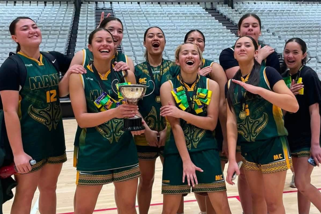 Mana College senior girls basketball team celebrating their College Sport Wellington Premier Girls championship win, with players holding the trophy and wearing medals.