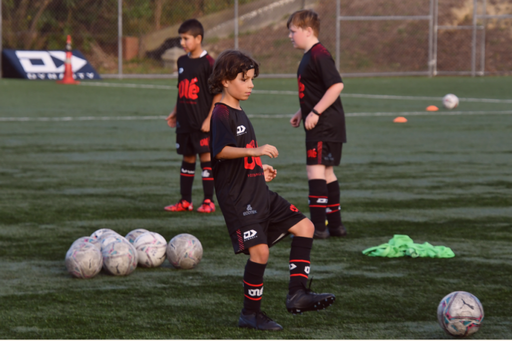 Young Olé Football Academy players training on a football pitch in Porirua.