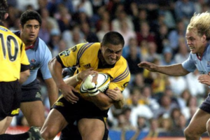 Jerry Collins carries the ball during a rugby match as opposition defenders close in.