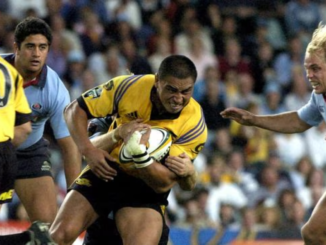 Jerry Collins carries the ball during a rugby match as opposition defenders close in.