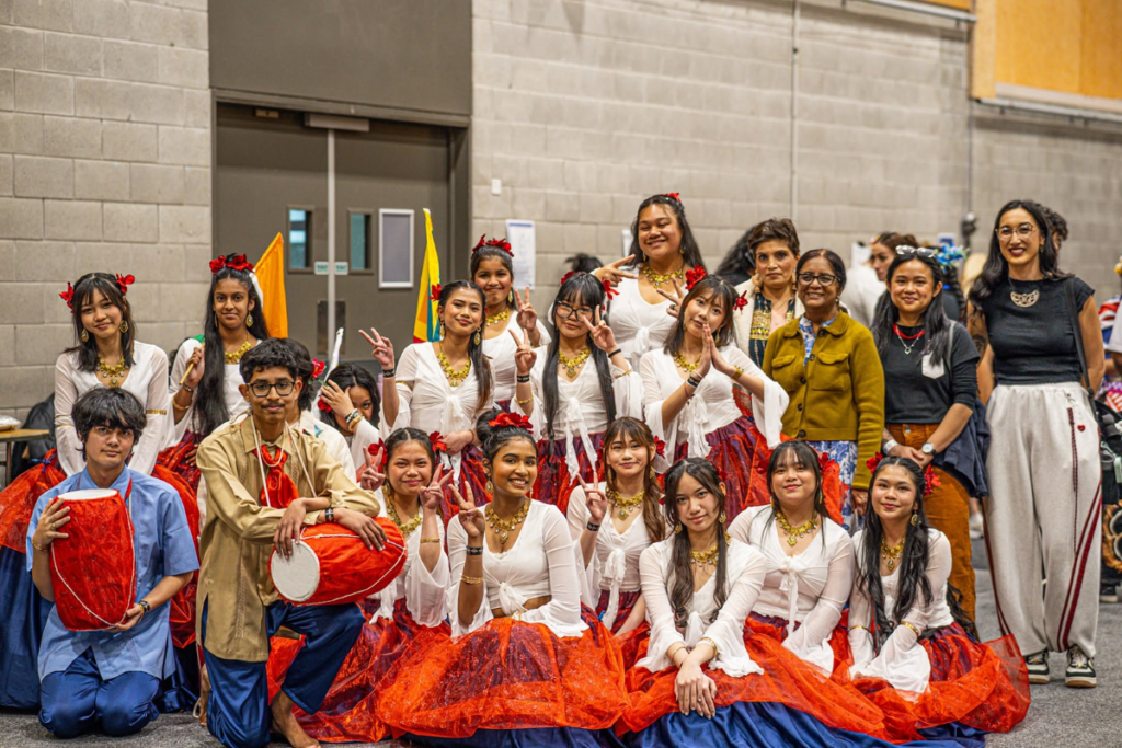 Mana College students and staff pose in cultural clothing during Asian Cultural Week, with two students holding drums.
