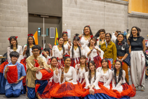 Mana College students and staff pose in cultural clothing during Asian Cultural Week, with two students holding drums.