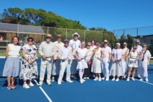 Plimmerton Community Tennis members dressed in 1920s-style clothing pose with wooden tennis rackets on the club courts during centenary celebrations.