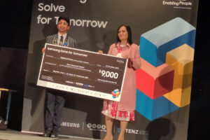 Gabriel Anthony, left, holding a large Samsung Solve for Tomorrow prize board with another person.