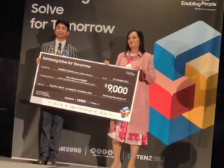 Gabriel Anthony, left, holding a large Samsung Solve for Tomorrow prize board with another person.