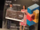 Gabriel Anthony, left, holding a large Samsung Solve for Tomorrow prize board with another person.