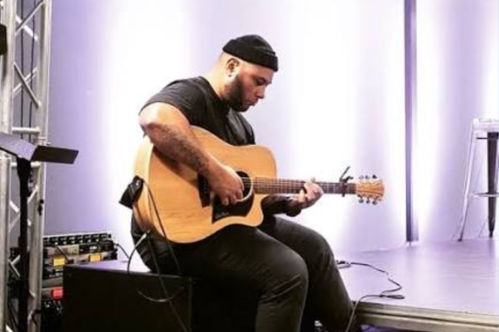 Porirua musician Pati Taii playing an acoustic guitar.