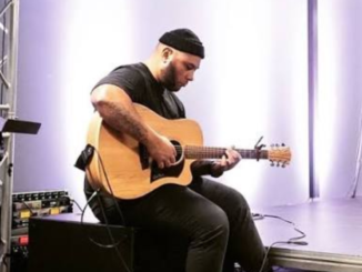 Porirua musician Pati Taii playing an acoustic guitar.