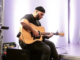 Porirua musician Pati Taii playing an acoustic guitar.